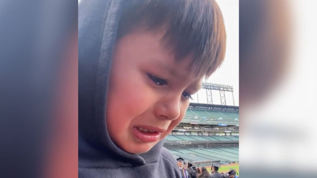 A little boy crying at his mom's graduation ceremony.