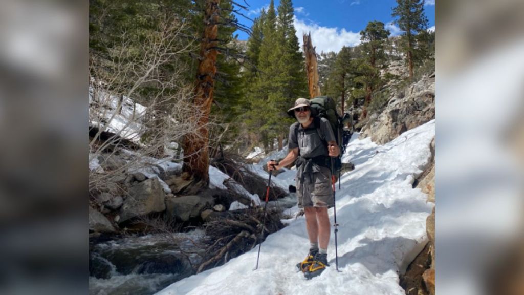 An elderly man hiking Mt. Whitney in the snow.