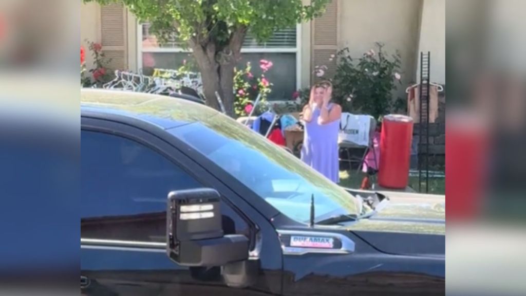 A woman across the street holds her head in her hands.