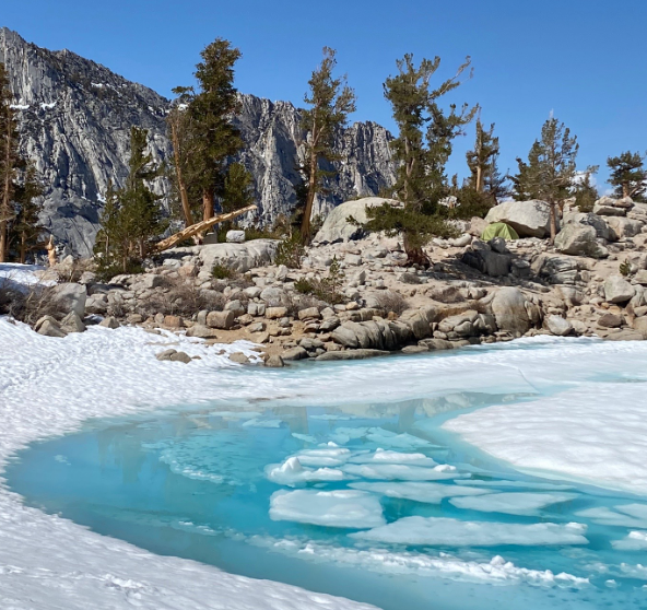 A frozen body of water next to a rocky slope.