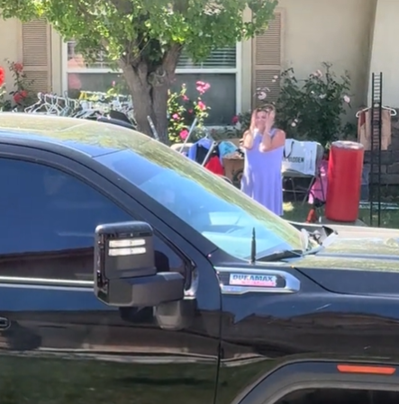 A woman across the street holds her head in her hands.