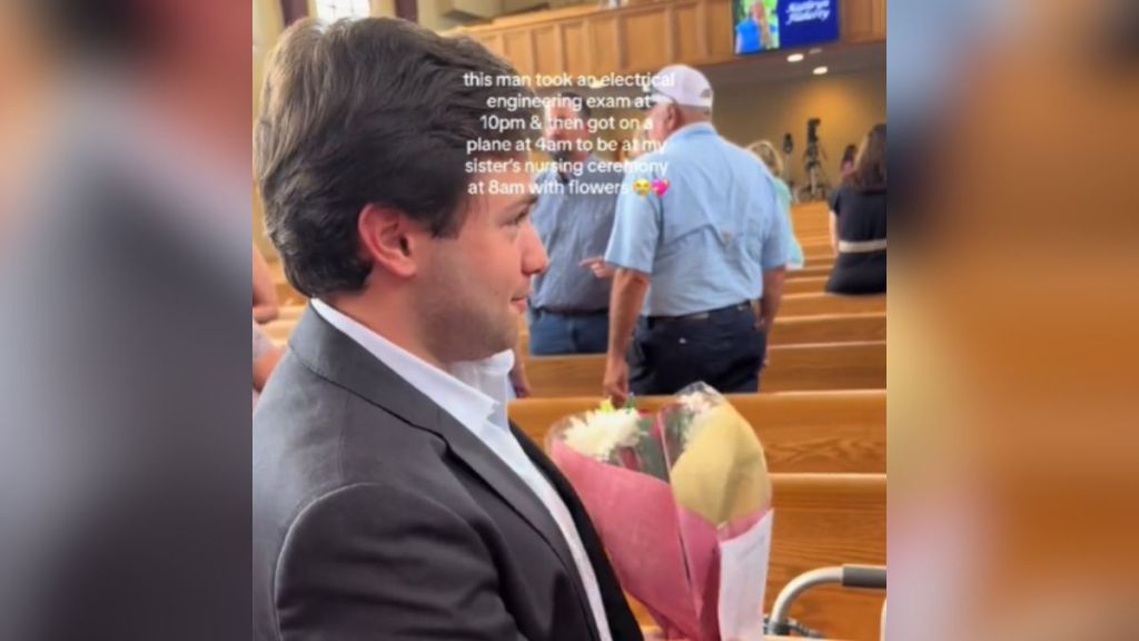 A boyfriend carrying flowers at a ceremony.