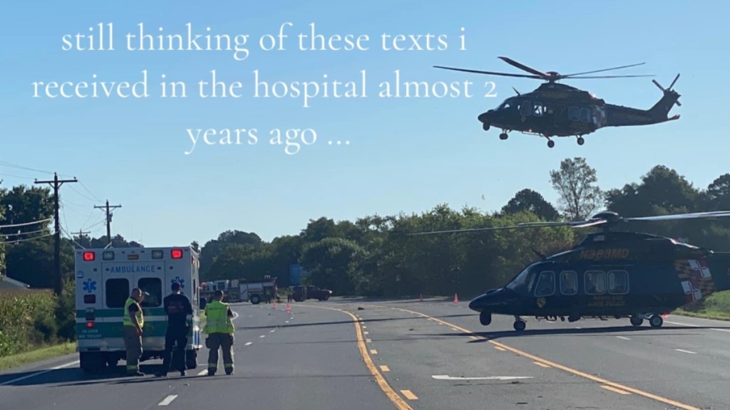View of a road after an accident. There's an ambulance on the side of the road, a helicopter on the road, and a helicopter in the air. Text on the image reads: still thinking of these texts I received in the hospital almost 2 years ago...