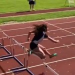 A track runner mid-jump over a hurdle during a race