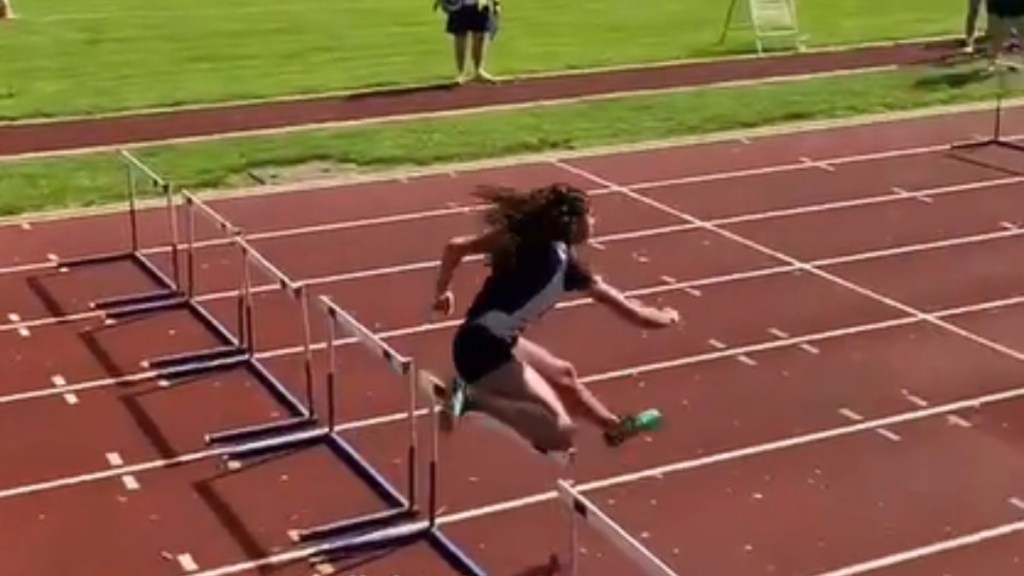 A track runner mid-jump over a hurdle during a race