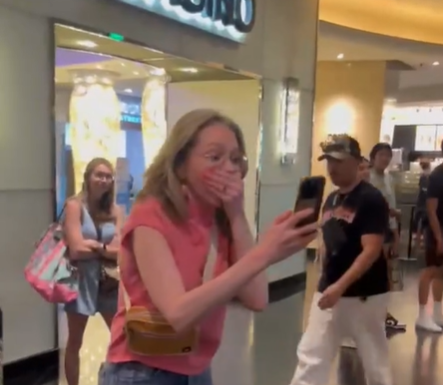A young woman holds her hand over her face in surprise.