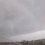 family running toward storm chaser during tornado