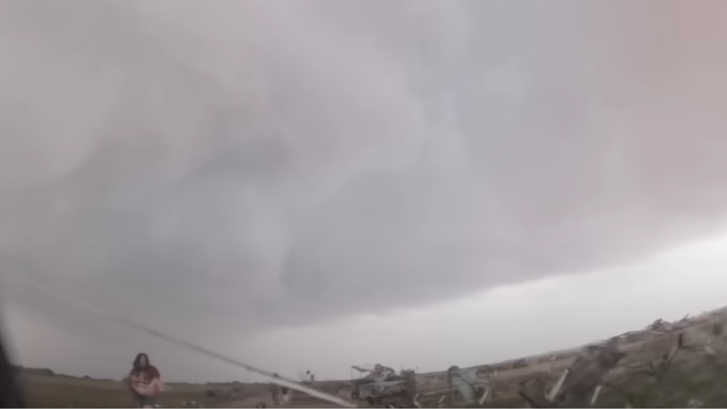 family running toward storm chaser during tornado