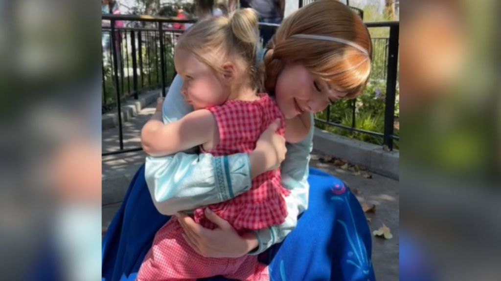 Anna from "Frozen" hugs a little girl at a Disney theme park.