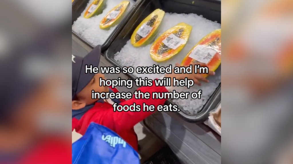A little boy reaches for packaged meat at the grocery store.