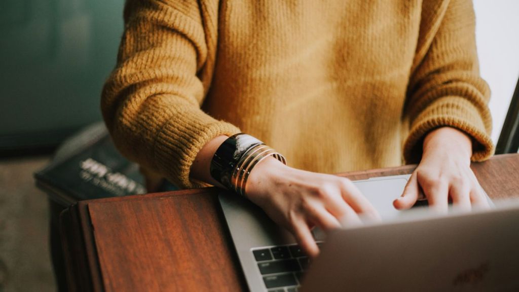 A woman's hands typing on a laptop.