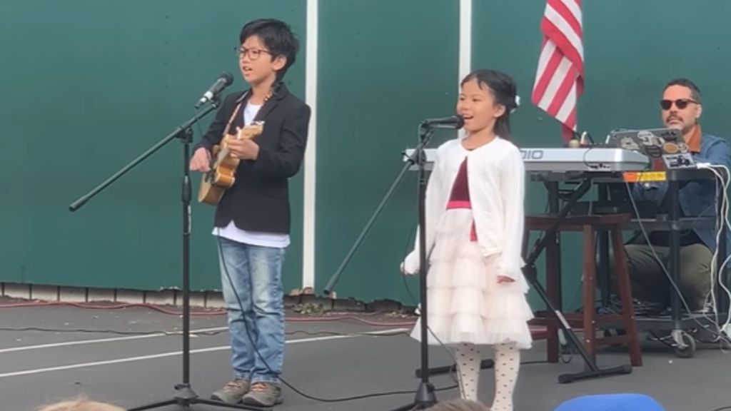 A brother and sister singing and playing music together.