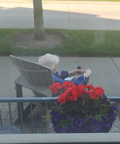 An elderly woman sitting in a chair outdoors.