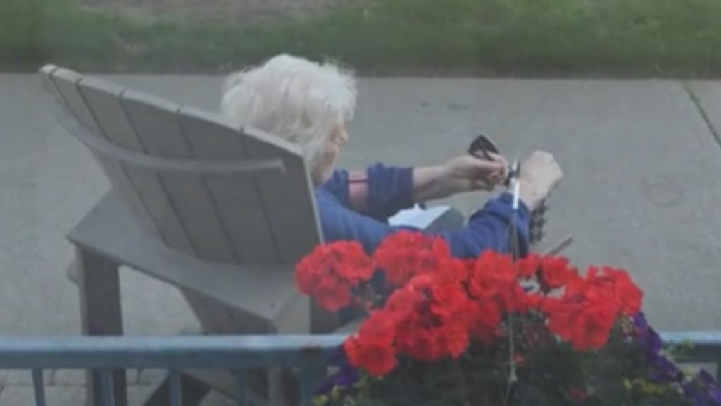 An elderly woman sitting in a chair outdoors.