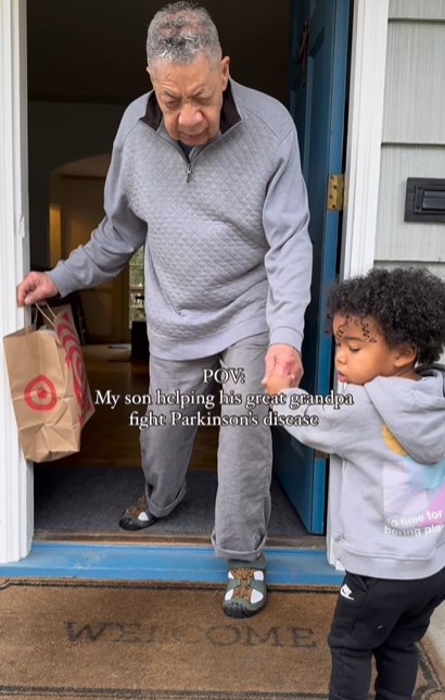 A little boy helping his great-grandpa walk out the front door.