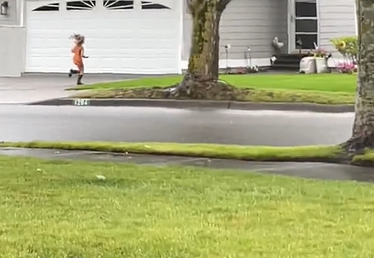 A little girl running down the driveway to a neighbor's house.
