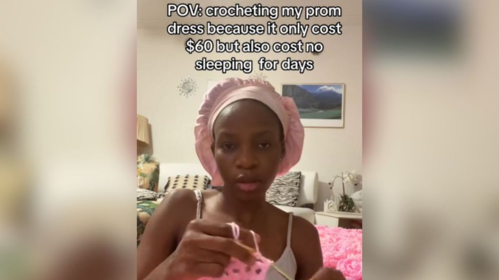 A young woman crocheting with pink yarn.