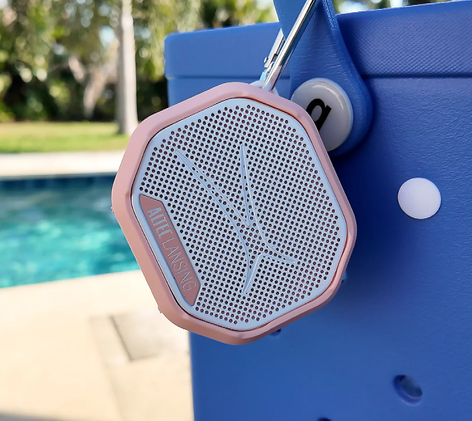 A portable speaker hanging outside next to a pool.