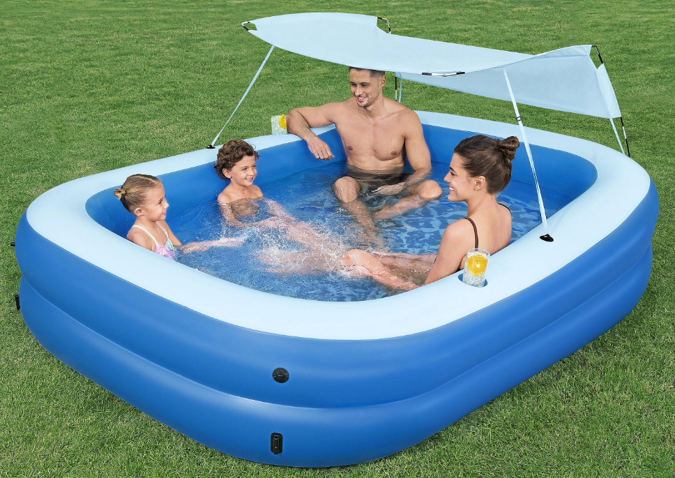 A family sitting in an inflatable pool outdoors.