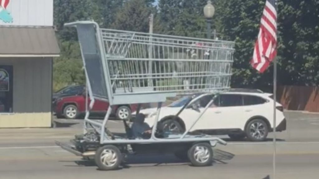 Image shows a giant grocery cart built on a vehicle frame with a rear-mounted engine being driven through Forks, WA.