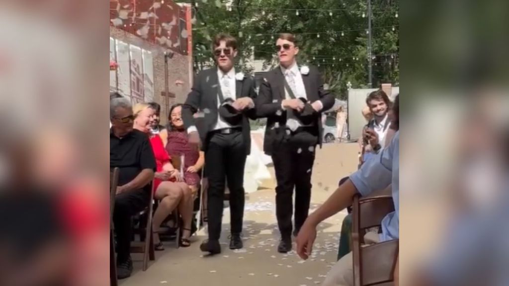 A pair of twins dressed in suits scattering petals at a wedding.