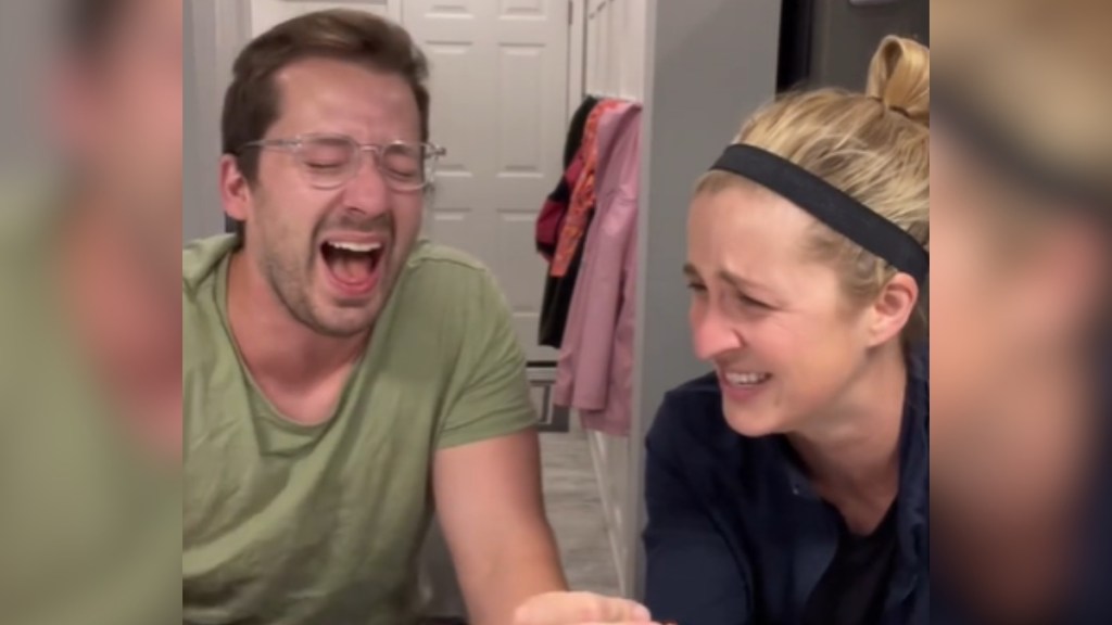 A man and woman lose it laughing as they sit next to each other