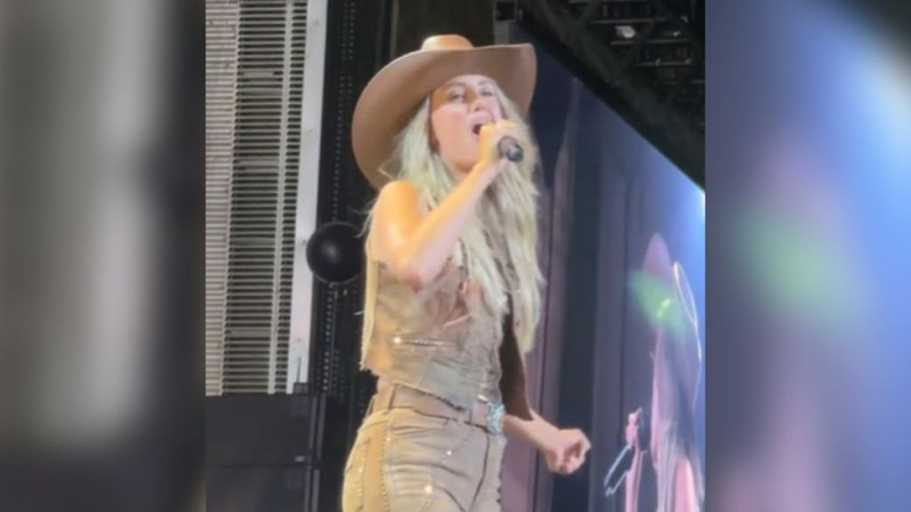 Lainey Wilson singing on stage wearing a cowboy hat.