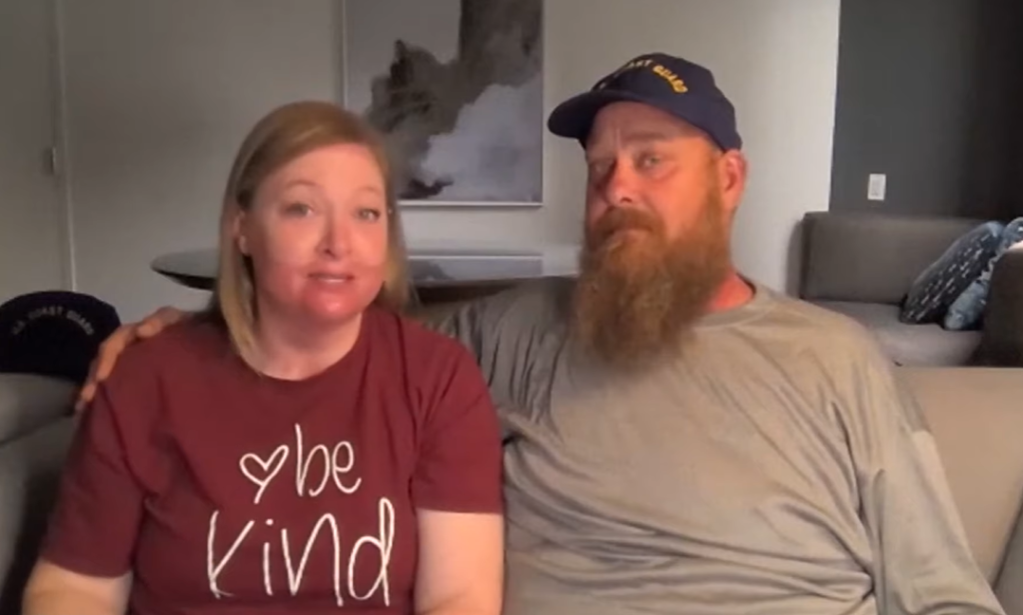Kim and Nathan sit on a couch next to each other. Kim talks while Nathan has an arm around her shoulder.