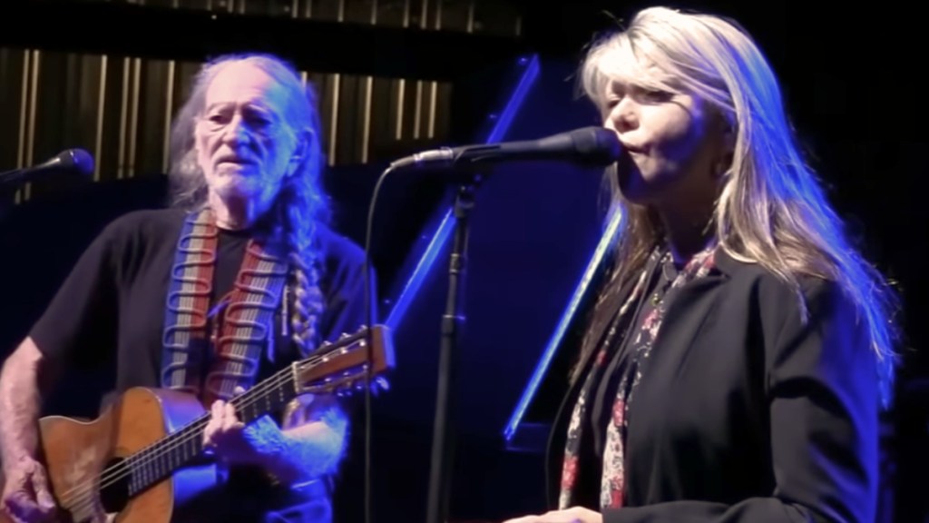 Willie Nelson and his daughter, Paula, stand next to each other on stage as they sing