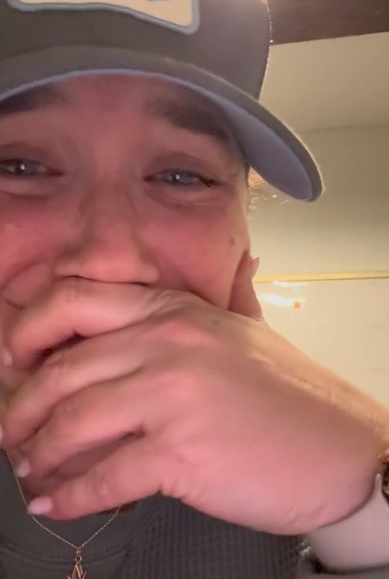 A woman covering her mouth with her hand during an emotional moment.
