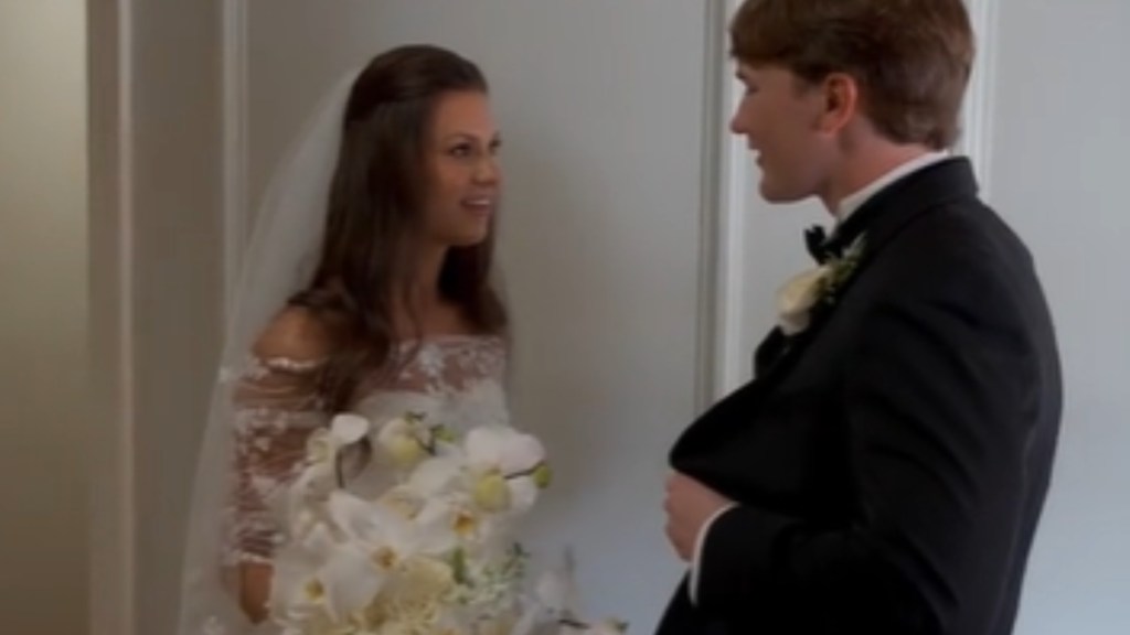 A smiling bride looks at her smiling groom who are talking to one another
