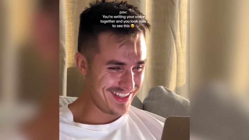 A man crying and smiling while writing his wedding vows.