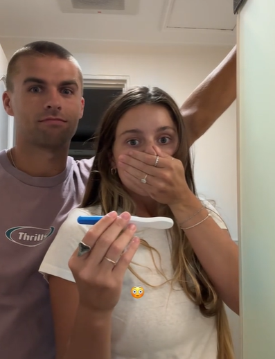 A woman and her husband look shocked at the results of a pregnancy test.