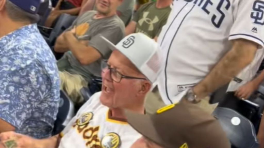 A grandpa looking happy in the crowd at a baseball game.