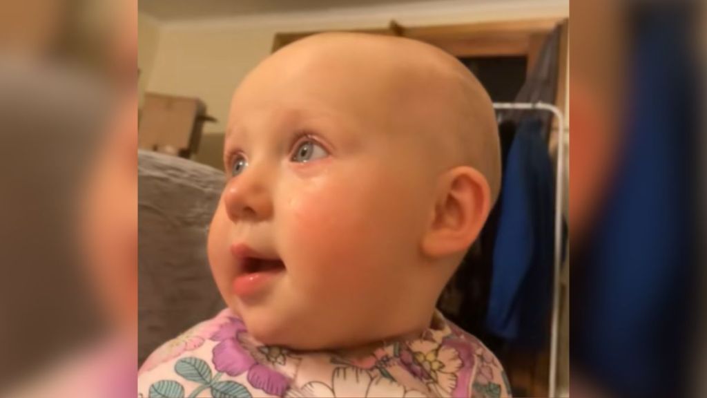 A baby with tears in her eyes looks into the distance with wonder.