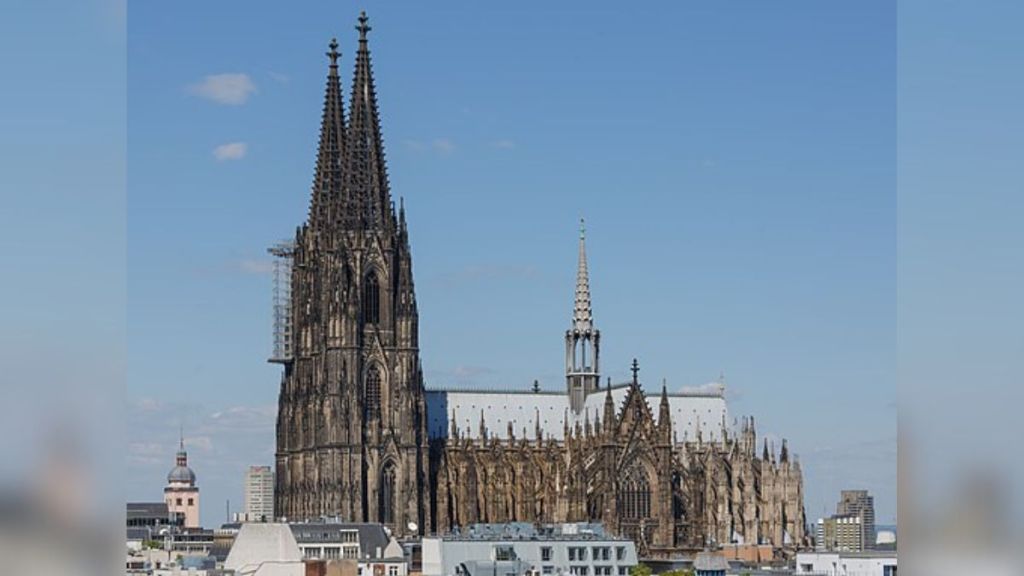 Stock image shows the Cologne Cathedral with its two towers against a blue sky background.