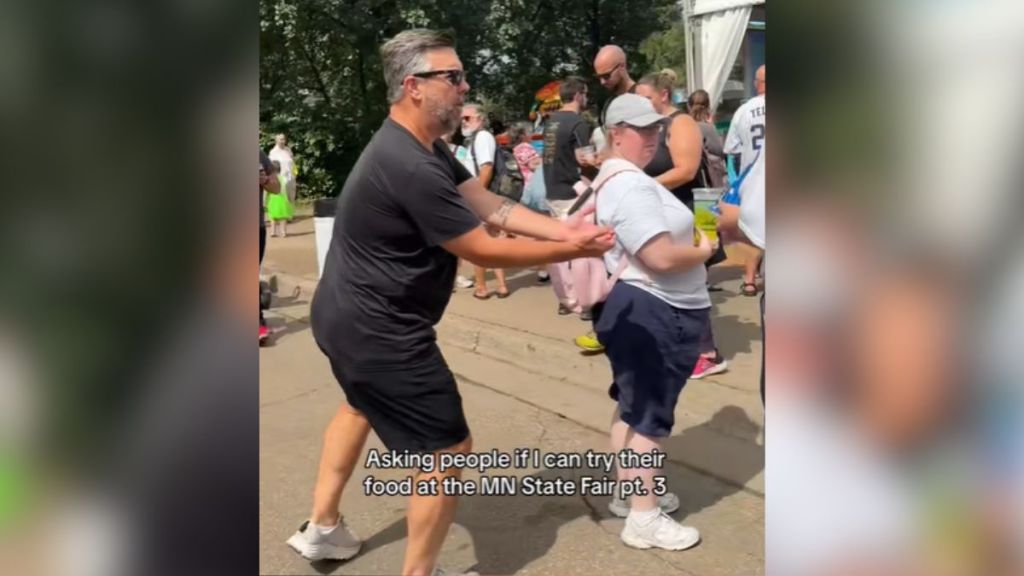 A man holds out his hands for food from strangers.