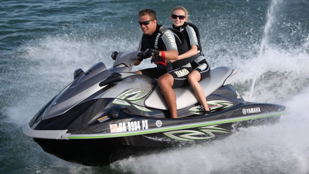 Stock image shows two people riding a jet ski.