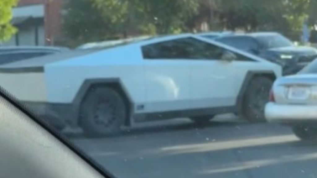 Image shows a Tesla Cybertruck in a parking lot with a white vinyl wrap.