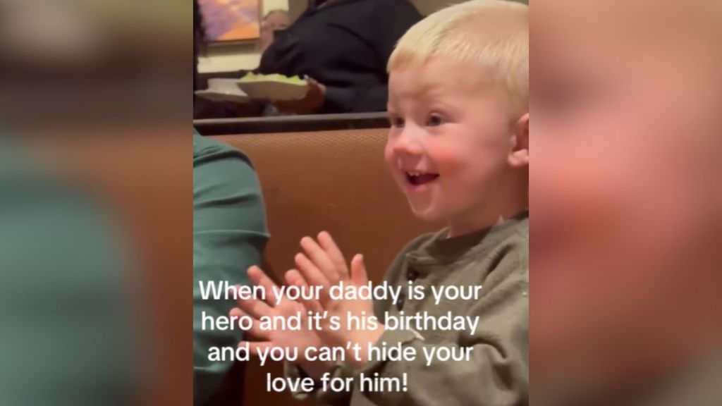 A little boy clapping and smiling in a restaurant.