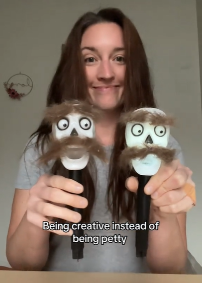 Madison smiles proudly as she holds up too outdoor skeleton lights. They are decorated with dog fur to look like mustaches and eyebrows
Text on the image reads: Being creative instead of being petty