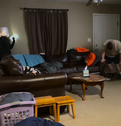 A man doubled over with laughter while his wife is dressed as a lamp.