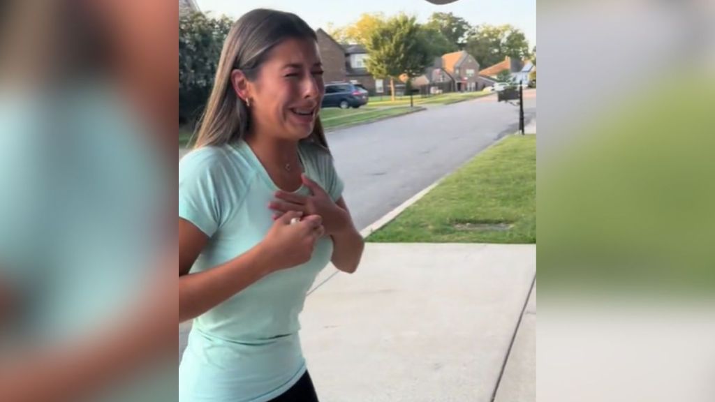 A young woman crying in the driveway of her home.
