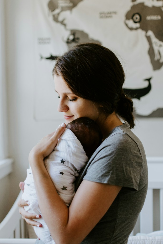 A mother holding a swaddled newborn baby.