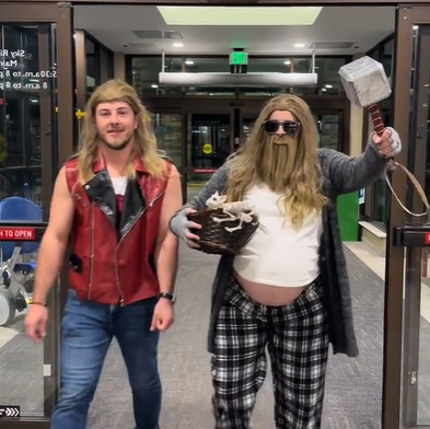 A husband and wife walking into a hospital, both dressed as Thor.