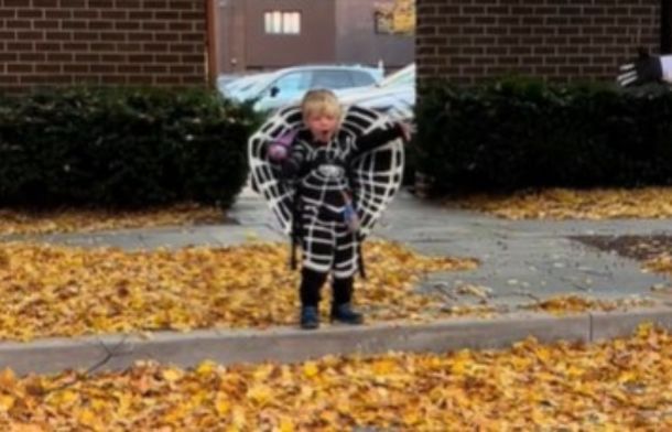 Image shows a child in a black hole costume standing on a curb.