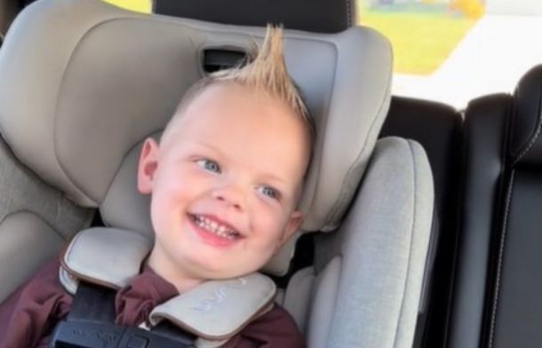 Image shows a toddler in a car seat, sporting a Mohawk hairstyle, smiling broadly while his mom plays the "Monkey Song" on the radio.