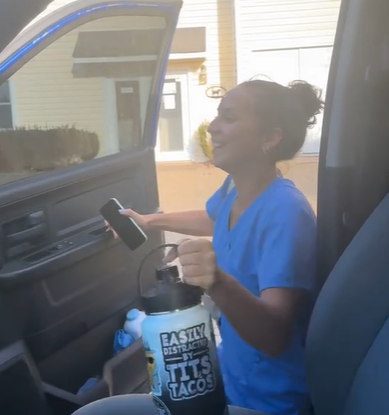 A woman in scrubs getting into the car.