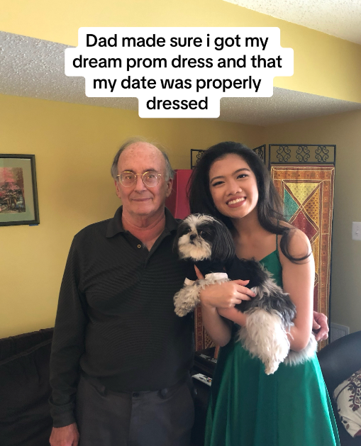 A young woman holding a small dog and standing next to her dad.