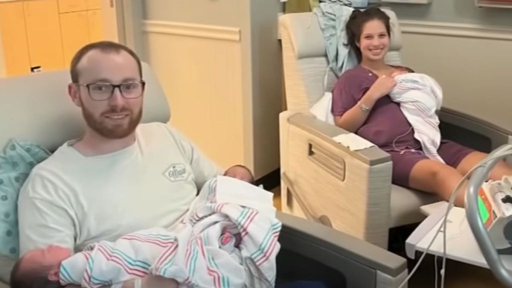 A man holding two babies next to a smiling woman holding one baby.